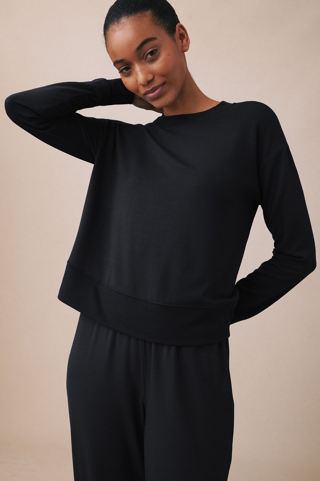 Black crewneck sweatshirt with ribbed trim worn with matching black joggers.