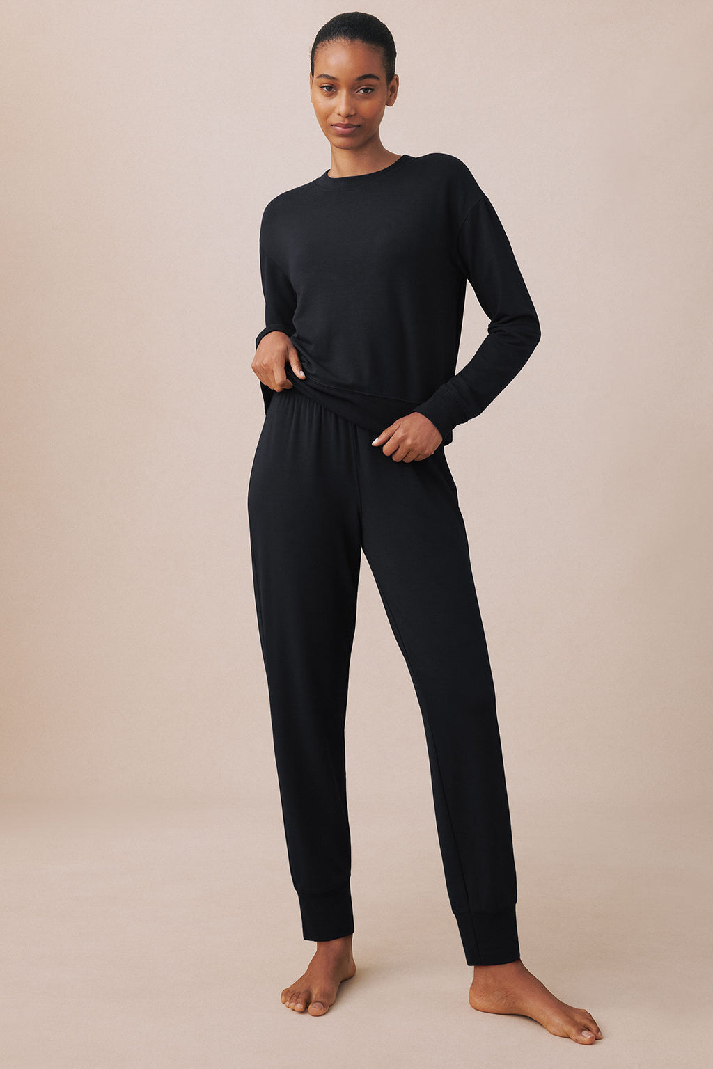 Black long-sleeve crewneck sweatshirt and jogger pants set on model.