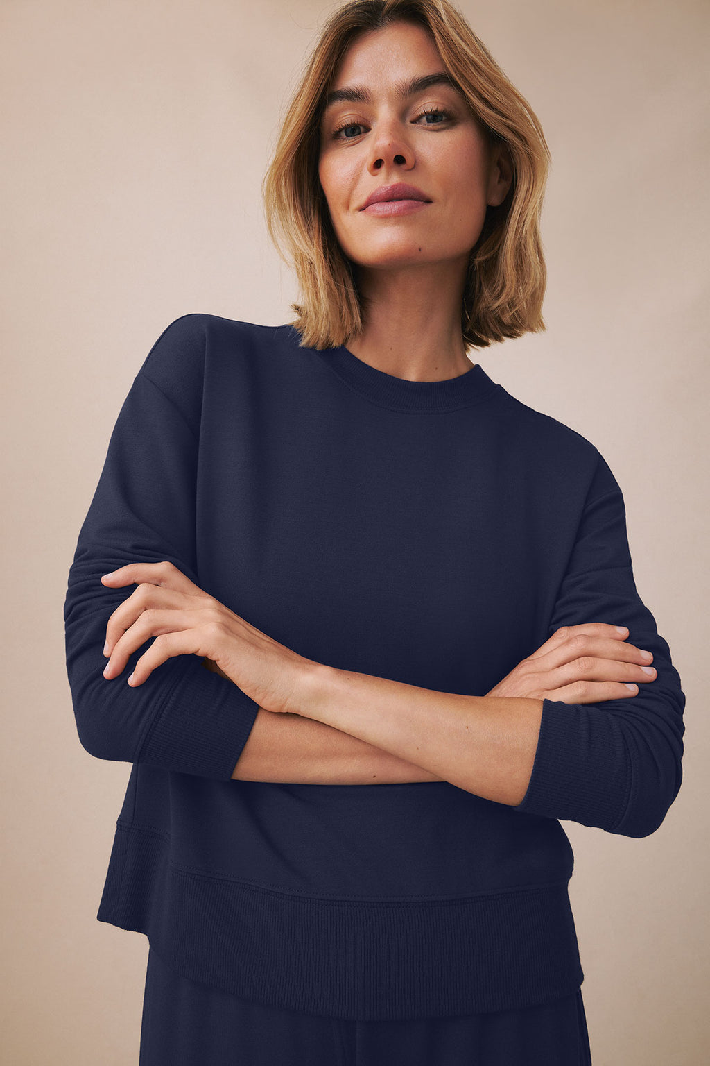 Woman wearing a navy crewneck sweatshirt with three-quarter sleeves and matching navy joggers.