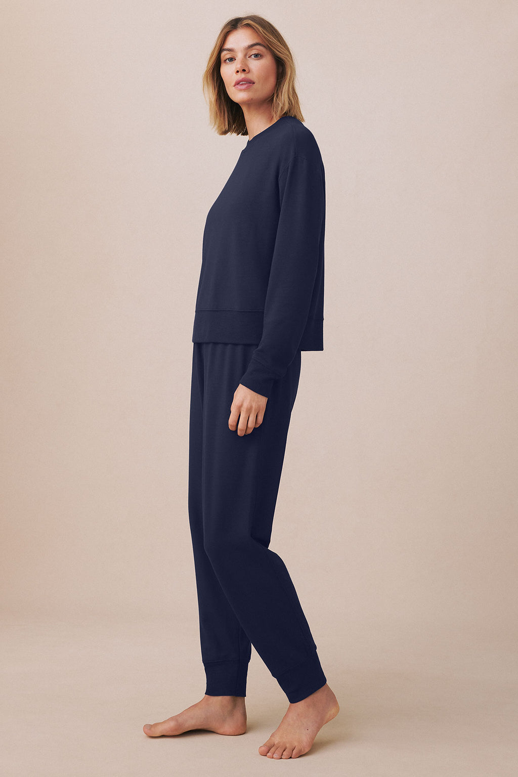Woman wearing a dark navy two-piece jogger set with a long-sleeve sweatshirt and matching tapered pants.