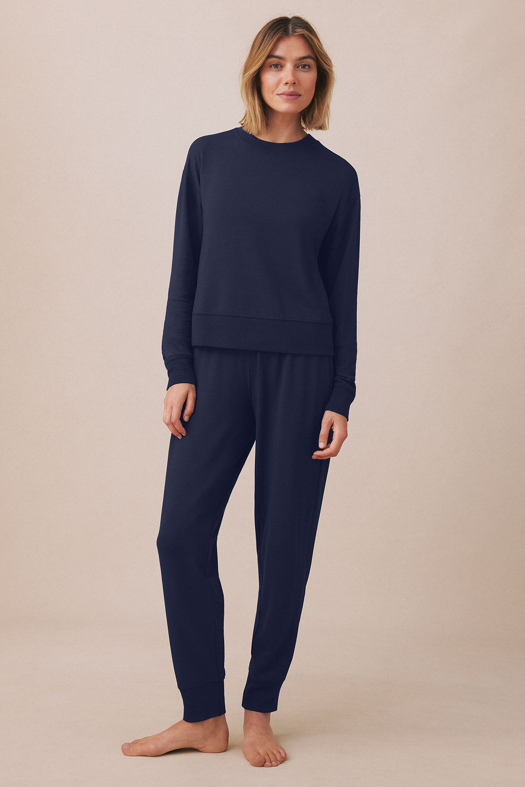 Woman wearing dark navy long-sleeve sweatshirt and matching tapered jogger pants.