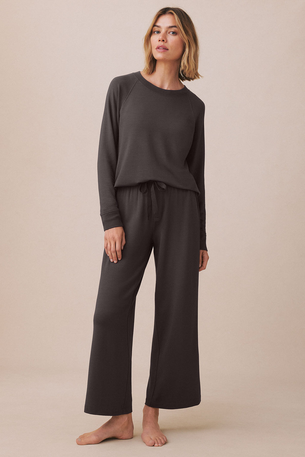 Woman wearing a dark gray long-sleeve crewneck top and matching wide-leg pants with drawstring waist.