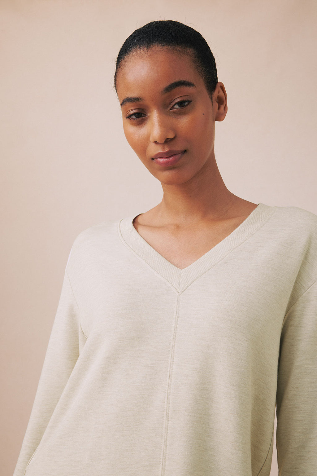 Oat heather V-neck long-sleeve top with center seam detail on model against neutral background.