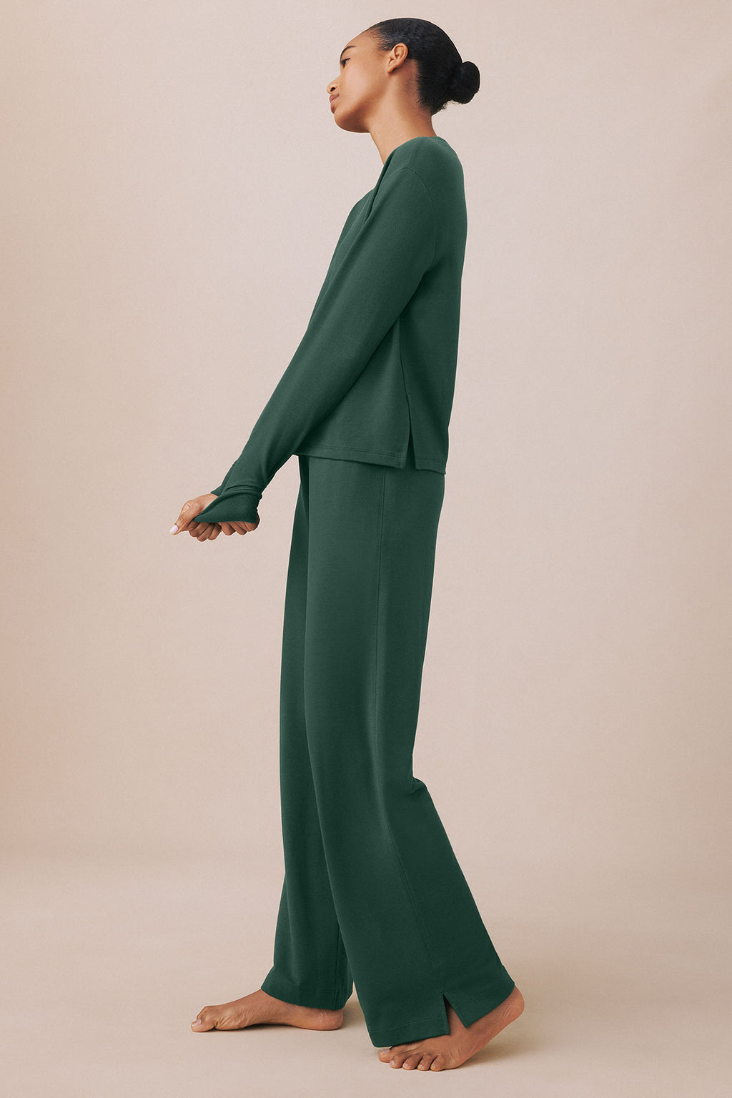Woman wearing a dark green V-neck long-sleeve top and matching wide-leg pants, shown in profile view.