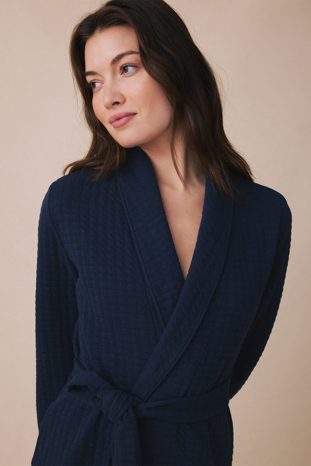 Navy blue spa robe with shawl collar and tie waist worn by model against neutral background.