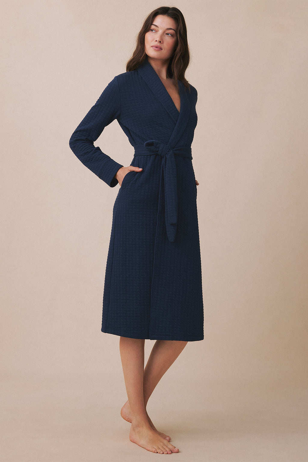 Navy blue quilted wrap robe with long sleeves, tie waist, and midi length, worn on a model against a neutral background.