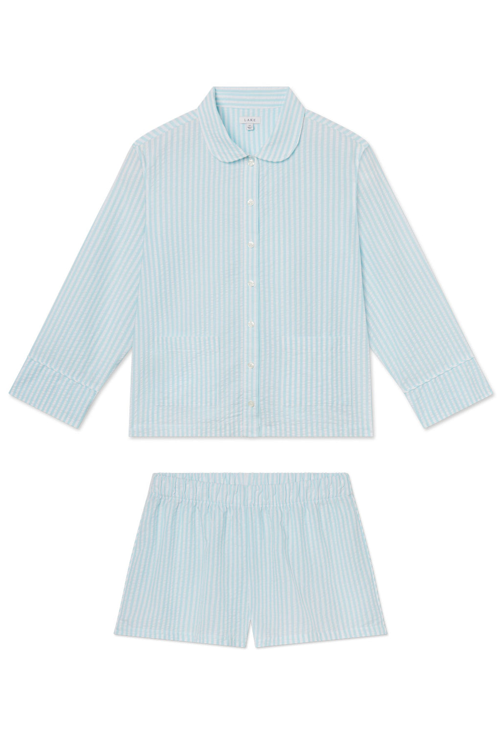 The Georgie Pocket Shorts Set in Salt Spray Seersucker includes a striped light blue and white long-sleeve collared top and matching elastic-waist shorts, both made from soft Pima cotton on a white background.