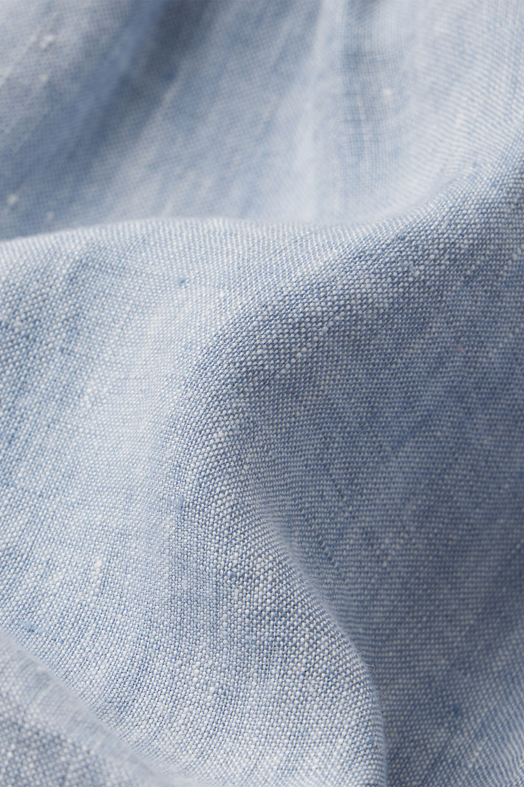 A close-up of light blue linen fabric from the Helen Dress in Blue Linen, highlighting its woven texture and soft folds.