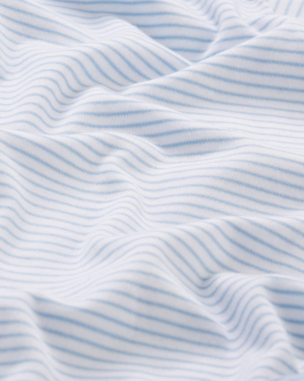 Close-up of the Baby Bodysuit Bundle in French Blue, crafted from 100% Pima cotton with thin, light blue horizontal stripes and soft folds that create a wavy texture on the fabric.