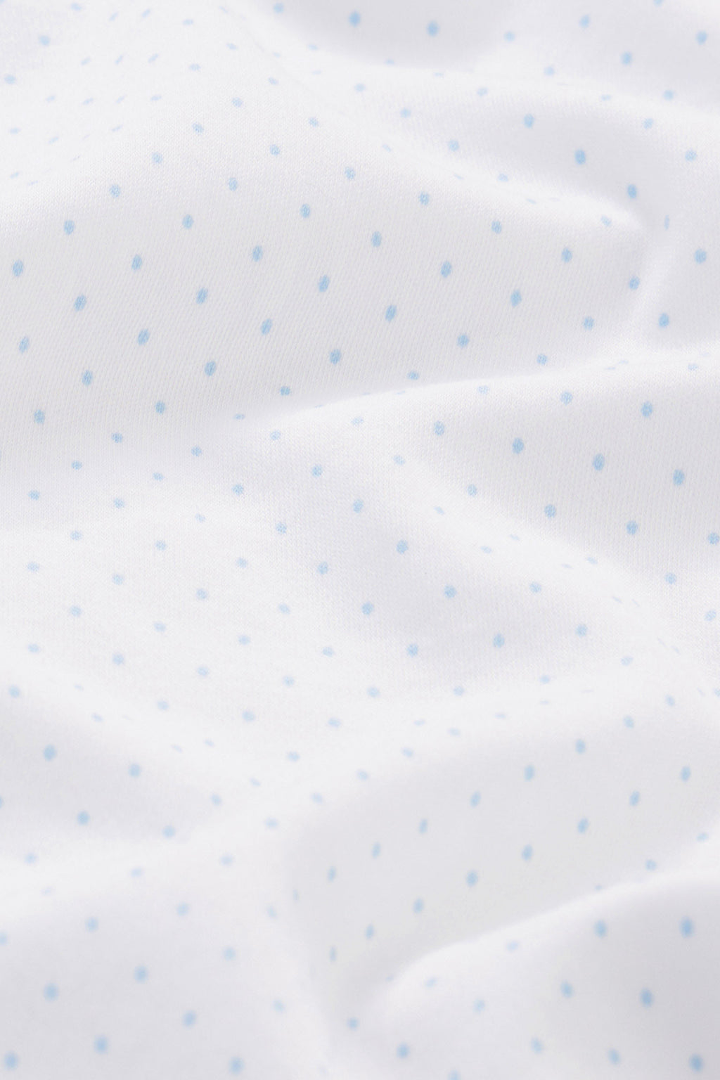 The Reversible Baby Blanket in French Blue Multi features soft, hypoallergenic white Pima cotton with small light blue polka dots and gentle folds—making it perfect for your baby’s comfort.