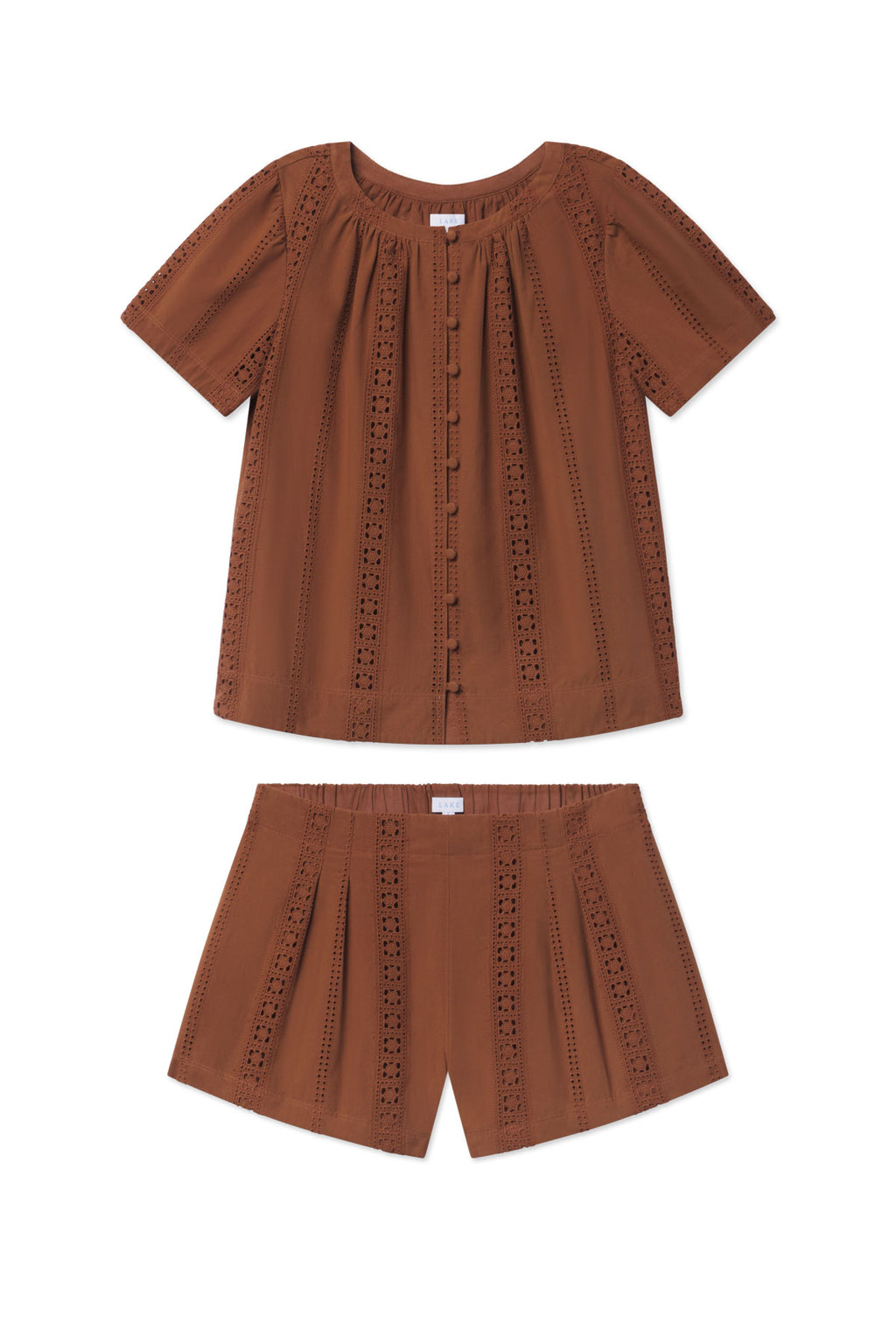 The Cafe Shorts Set in Cinnamon Eyelet features 100% cotton, a short-sleeve button-front blouse, and matching high-waisted shorts—both shown laid flat on a white background.