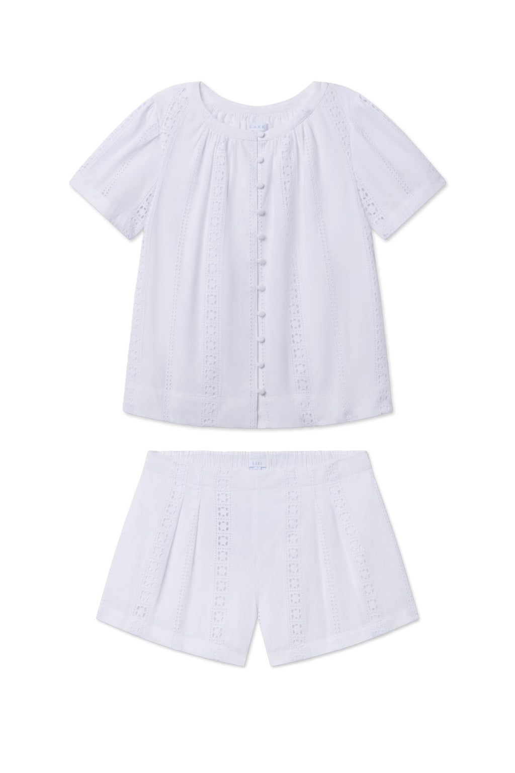 The Cafe Shorts Set in White Eyelet is a lightweight cotton two-piece for kids, featuring a short-sleeve button-front top and matching shorts for cool comfort and breathability.