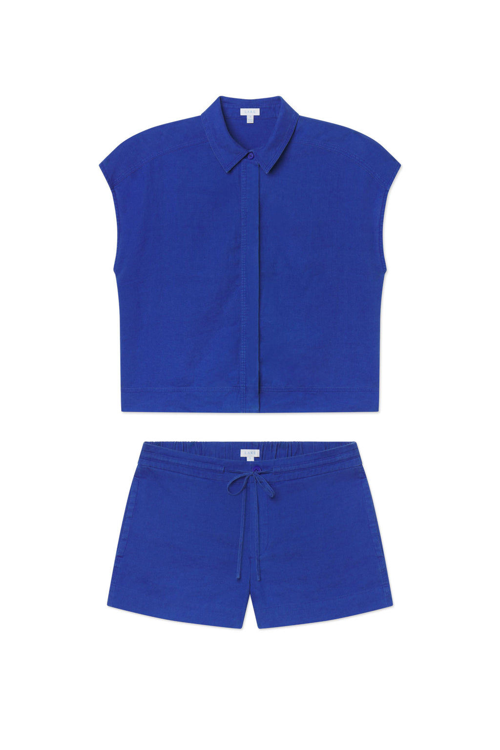 The Cruise Short Set in Lapis features a sleeveless, collared, button-up crop top and elastic waistband shorts in royal blue linen, both shown against a white background.