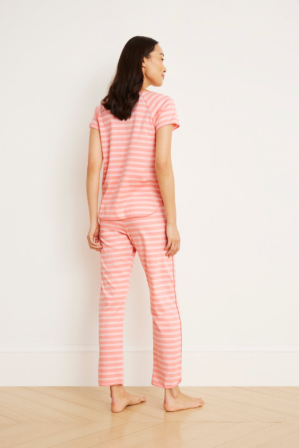 Woman wearing coral and white striped short-sleeve top and matching cropped pants, shown from behind.