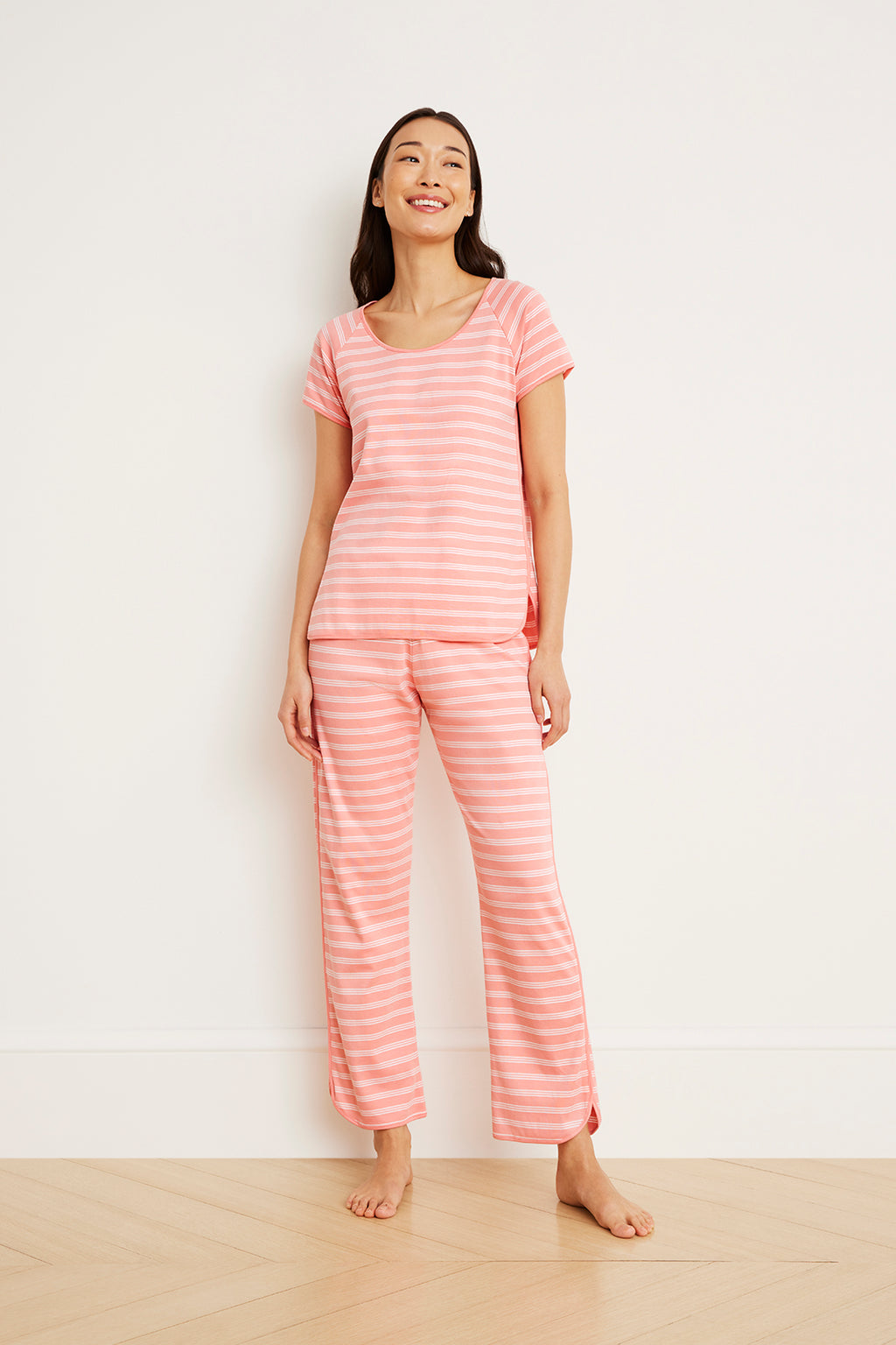 Woman wearing coral and white striped short-sleeve top and matching full-length pants.