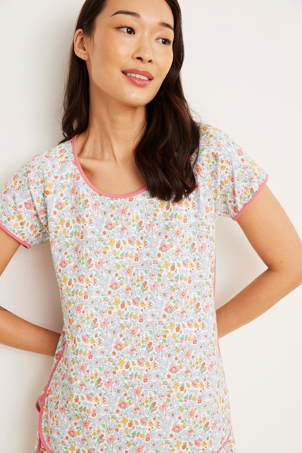 Woman wearing short-sleeved t-shirt with multicolored floral print and pink trim.