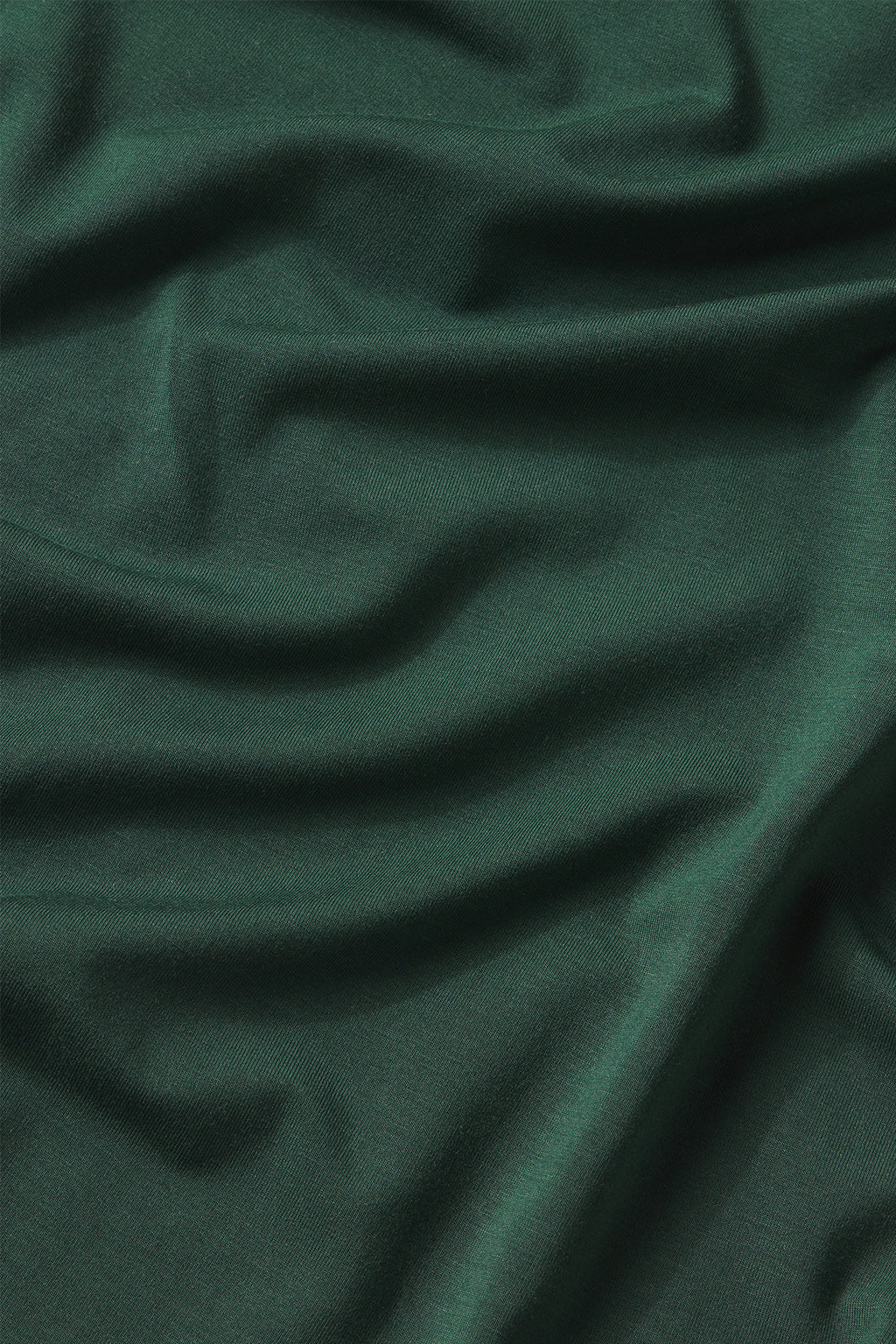 The DreamModal Ribbon Long-Long Set in Conifer features dark green fabric with soft folds and creases that create a textured surface and gently flowing pattern.