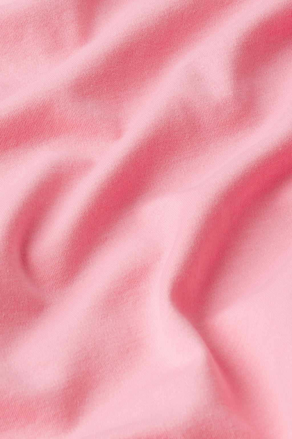 Close-up of the Pima Scallop Robe in Rosewater, featuring soft light pink Pima cotton fabric with gentle folds and a subtle texture that creates delicate shadows and highlights.