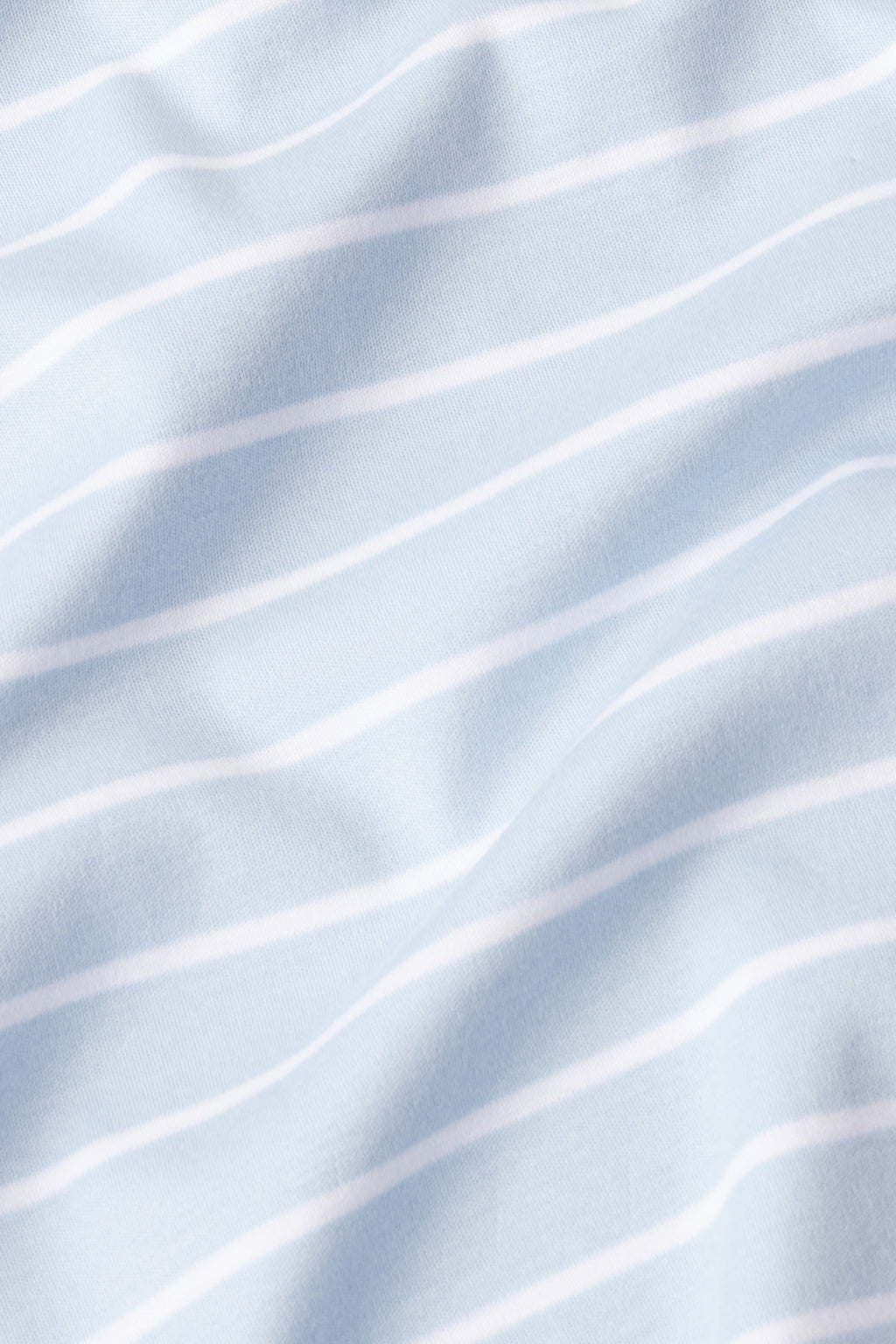 The Pima Short-Long Set in French Blue Club Stripe features light blue fabric with thin, evenly spaced white stripes. Its soft texture and gentle folds make it a breathable, comfortable choice for pajamas.