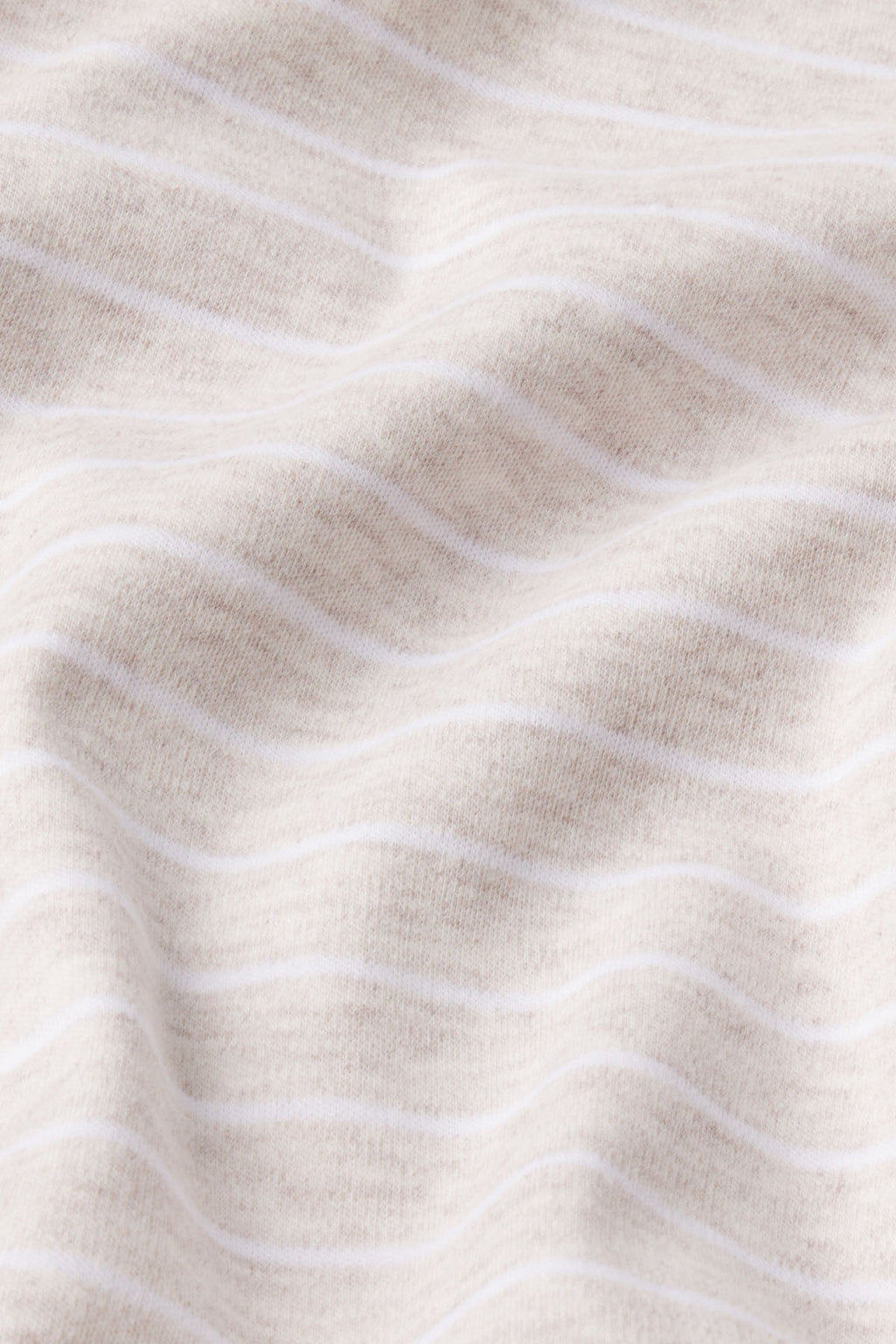 A close-up of the Pima Crew Shorts Set in Oat Heather Rowing Stripe shows soft beige Pima cotton with thin white horizontal stripes and gentle folds for a textured look.