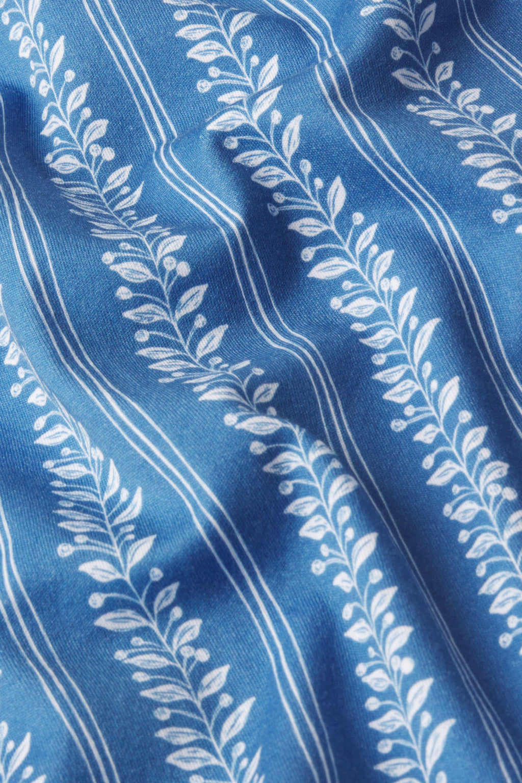 The Pima Bundle in Seaport Jasmine Vine features blue Pima cotton with a vertical botanical stripe of leafy vines and a slightly wrinkled texture for added dimension.