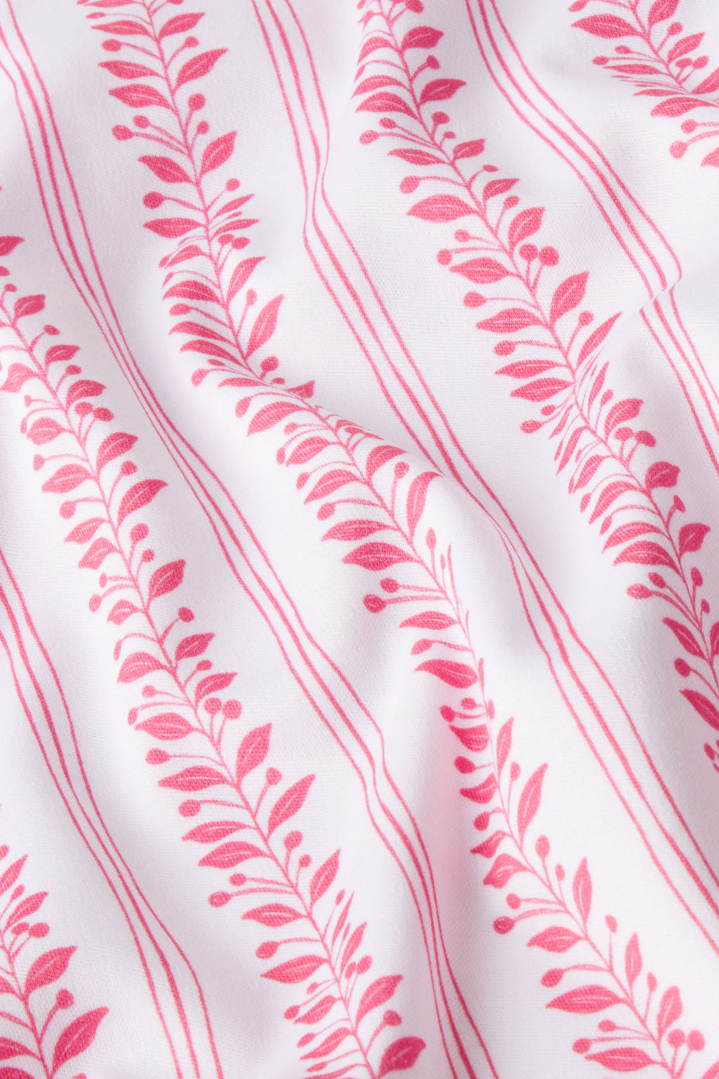 The Pima Nightgown in Winterberry Jasmine Vine features pink leafy vines and parallel lines on white Pima cotton, with gentle folds that create soft shadows and texture.