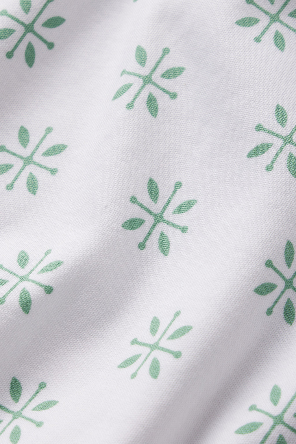 White fabric featuring green, symmetrical Moroccan blockprint patterns, each with six-line abstract floral shapes. Ideal for a stylish Pima Crew Long-Long Set in Boxwood.