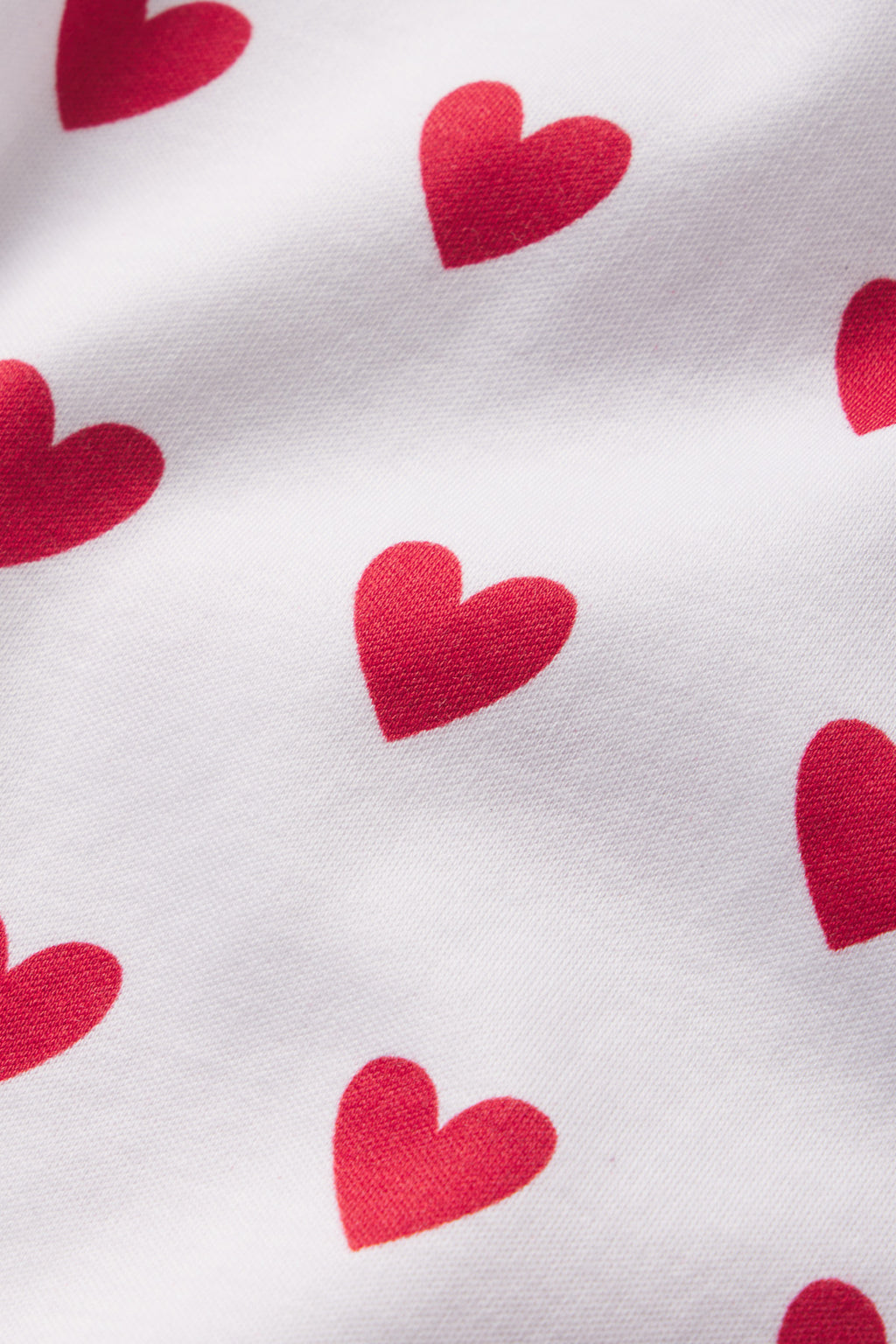 The Pima Shorts Set in Classic Red Heart features white 100% Pima cotton fabric with evenly spaced red hearts, subtle folds, and shadows for a timeless look.