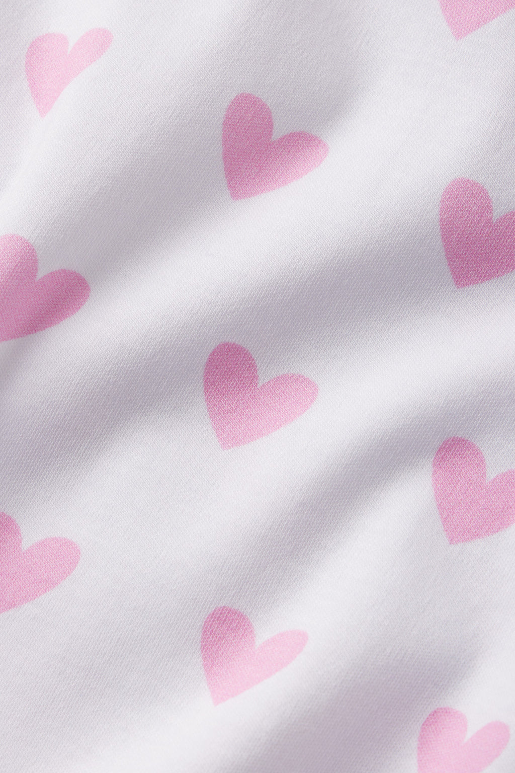 The Pima Crew Long-Short Set in Darling Pink Heart features soft white Pima cotton fabric adorned with playful pink heart motifs and gentle folds for a cozy, comfortable feel.