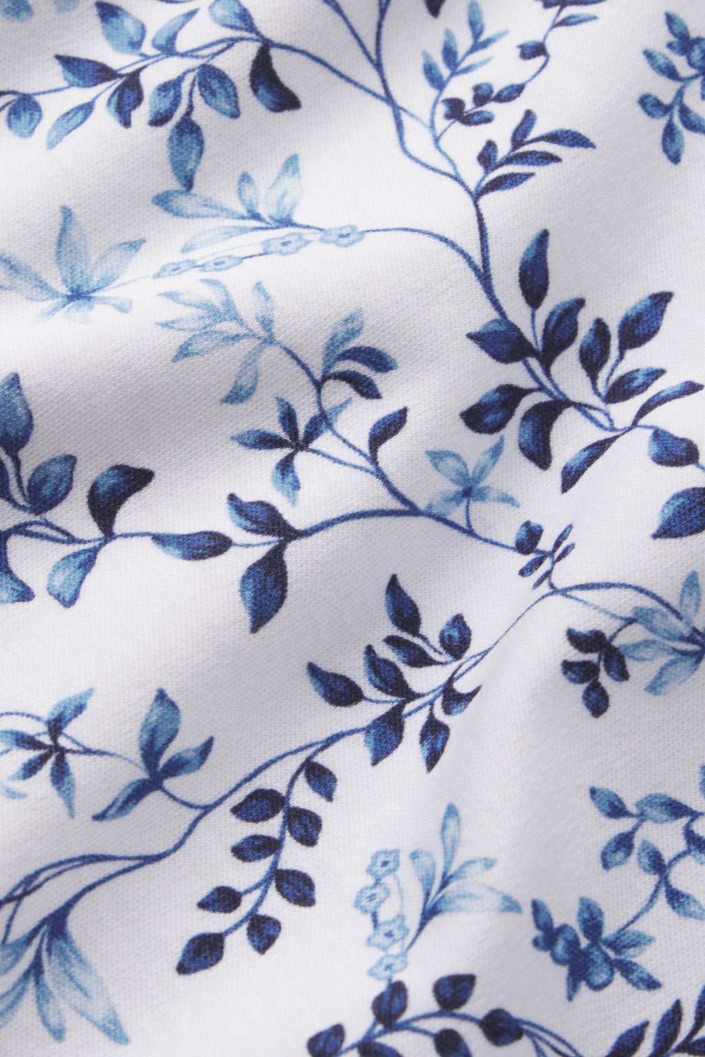 The Pima Ruffle Pants Set in Serene Blue Botanical Vines features white fabric with a blue floral pattern of delicate leaves and branches, crafted from 100% Pima cotton with subtle creases and visible texture.