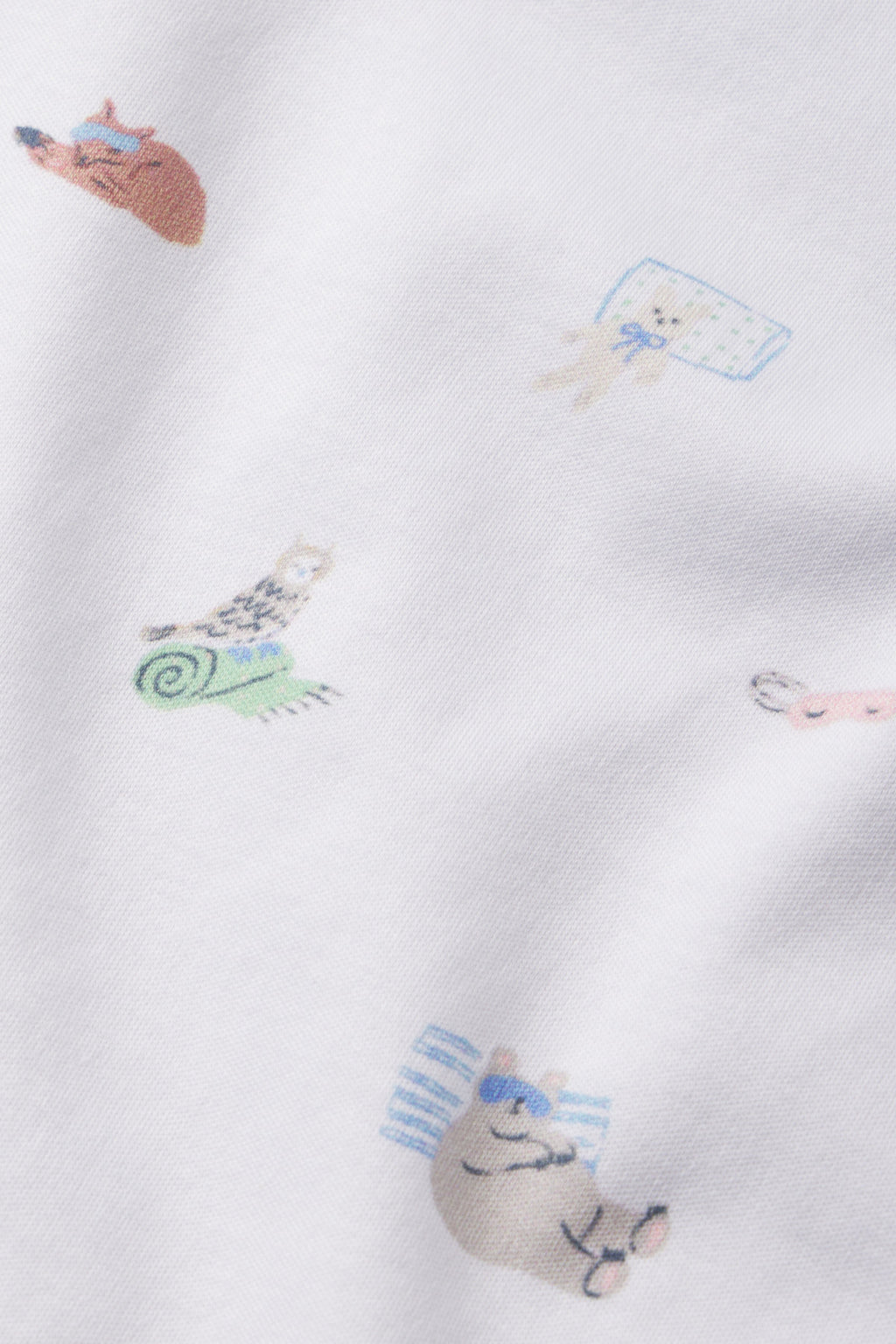 White Pima cotton Kids Long-Long Set in Slumber Party, featuring small printed illustrations of sleepy woodland animals—bear, dog, and rabbit—resting on pillows and mats scattered across the fabric.