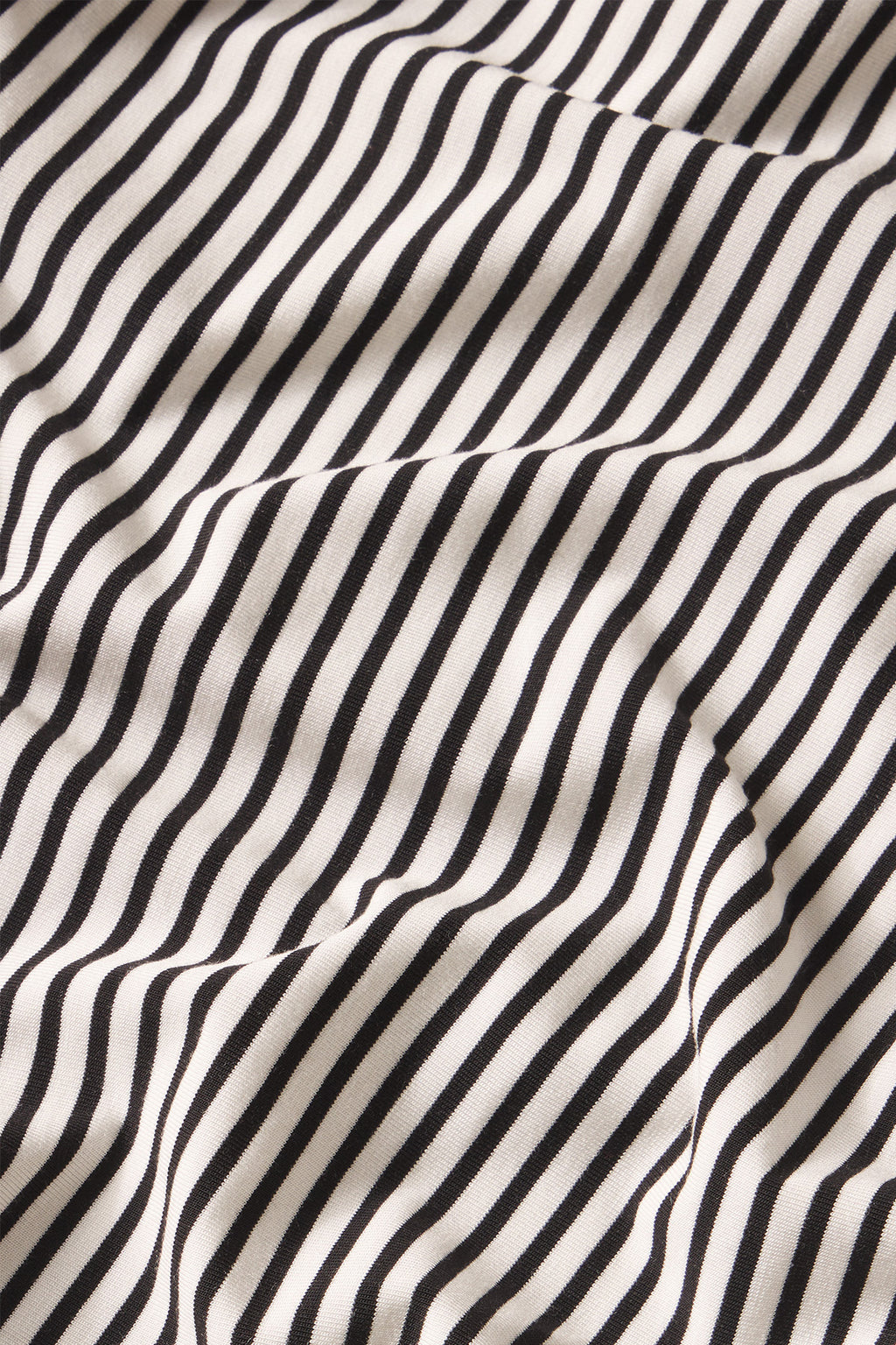 A close-up of the DreamModal Kimono Pajama Set in Black Pencil Stripe shows soft folds creating a dynamic, slightly distorted black and white striped pattern, emphasizing its nursing-friendly design.