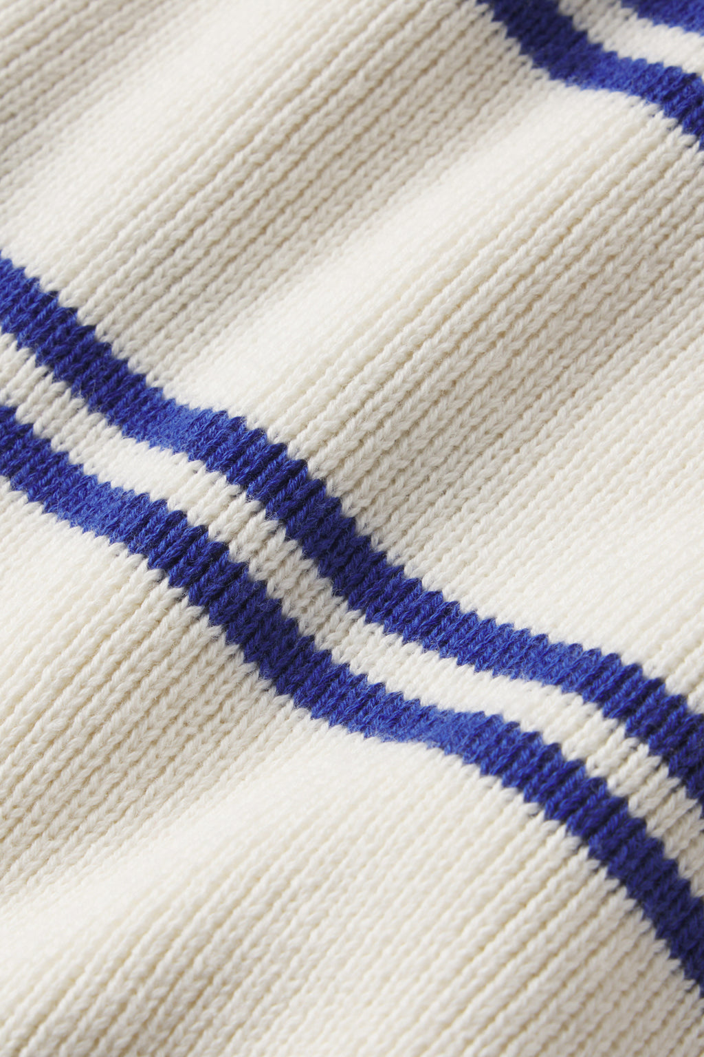 Close-up of the Nora Cardigan in Ivory Caspian Stripe, a ribbed, cream-colored varsity sweater with two parallel navy blue stripes. The knit texture and stripe design are clearly highlighted.
