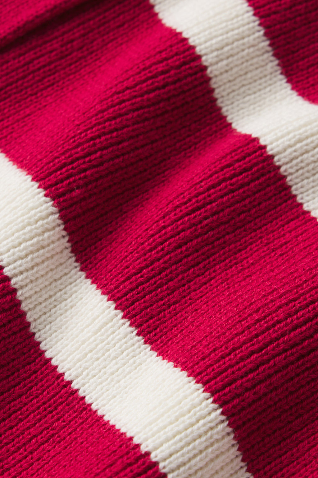 Close-up of knitted fabric from the Nora Cardigan in Ivory Crimson Inverse Stripe, showcasing horizontal stripes and visible yarn texture that highlights its soft, cozy material.