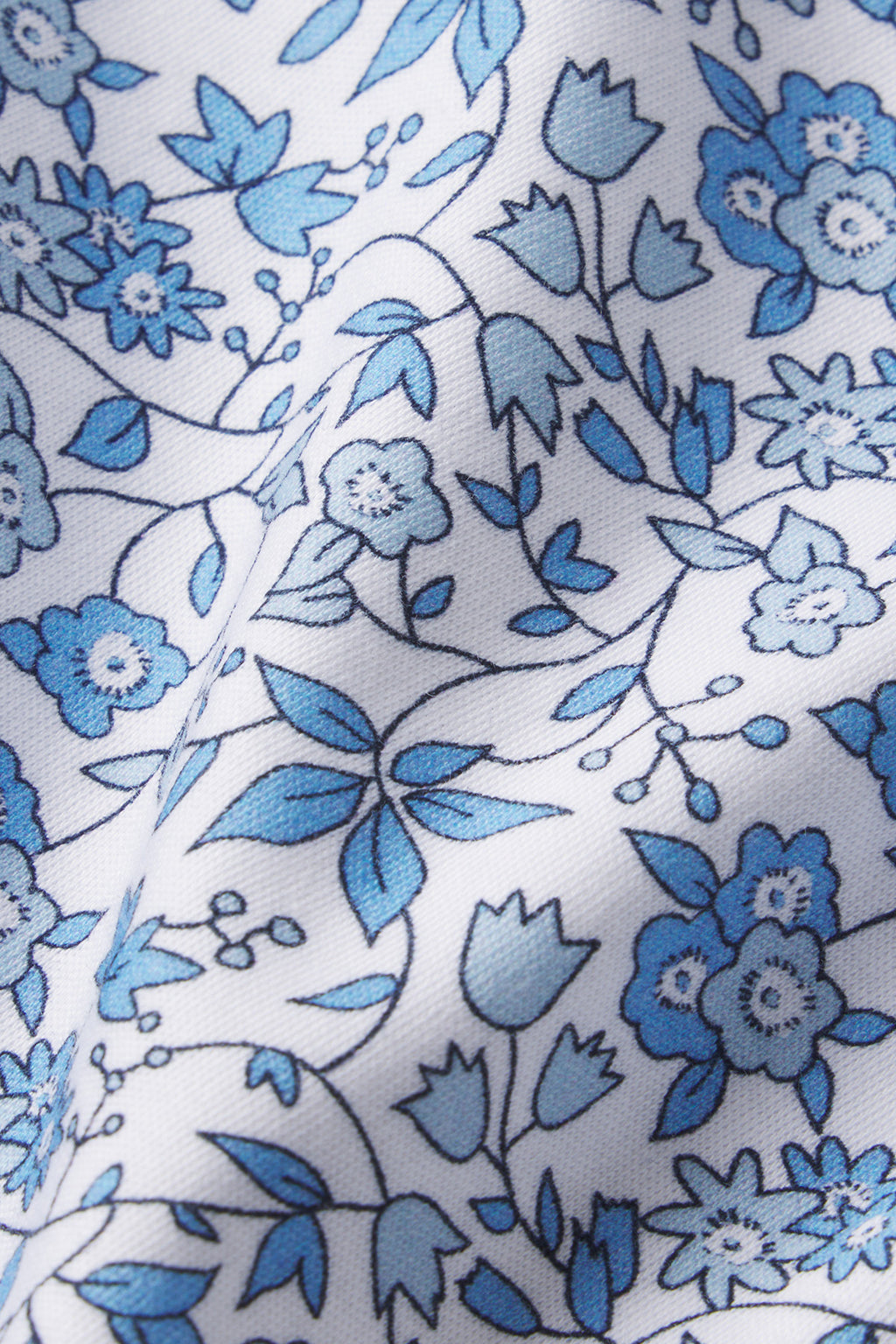 The Pima Maternity Nightgown in Delft Blue Garden Floral features soft white Pima cotton adorned with blue floral patterns and subtle folds, offering comfort and style for maternity and nursing wear.