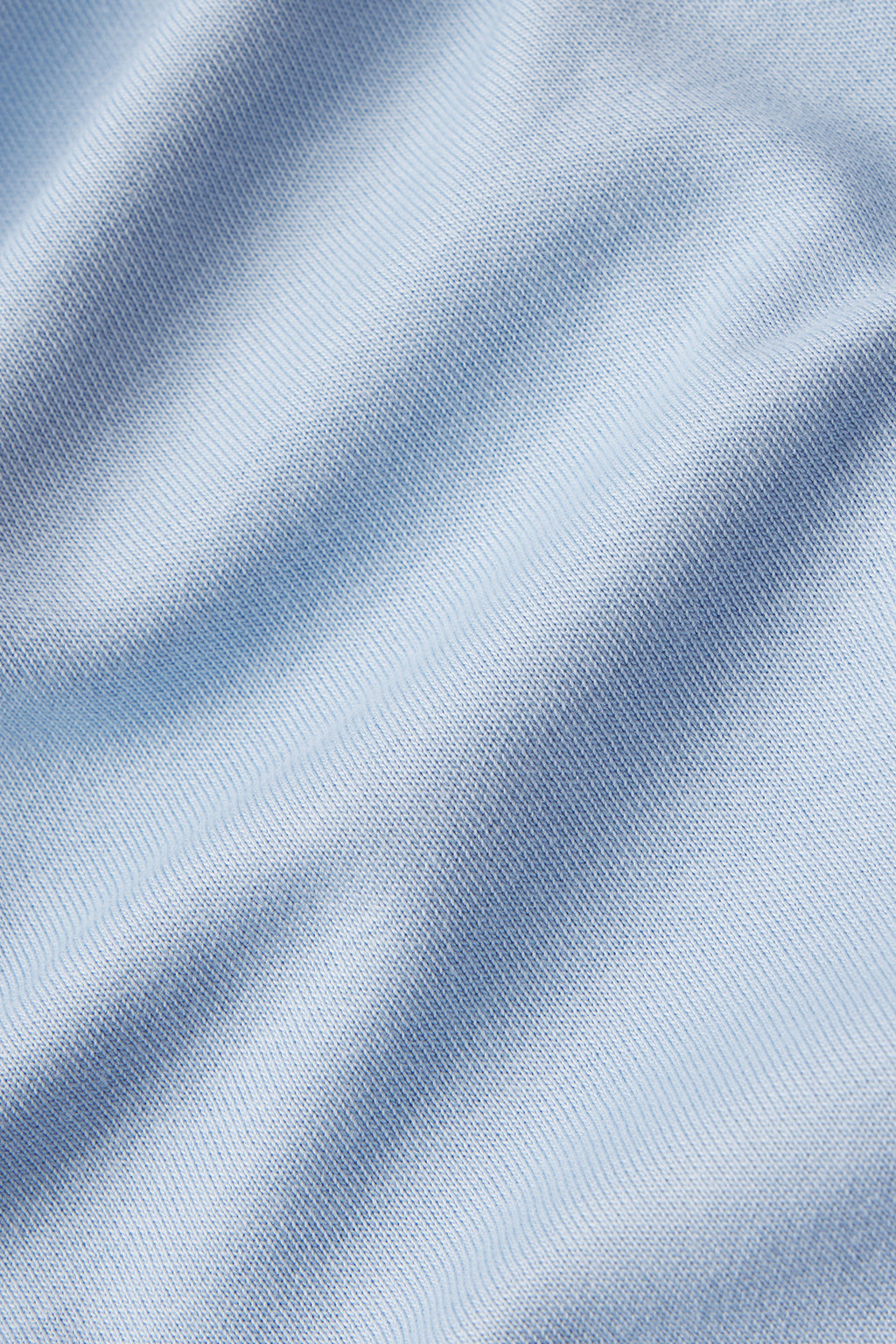 Close-up of light blue Pima modal fabric with soft folds and a subtle ribbed texture, creating gentle shadows and highlights—perfect for the Leisure Quarter Zip in Morning Blue.