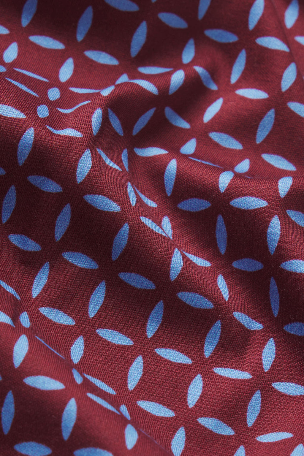 Burgundy fabric with blue starburst pattern, close-up of textured knit material.
