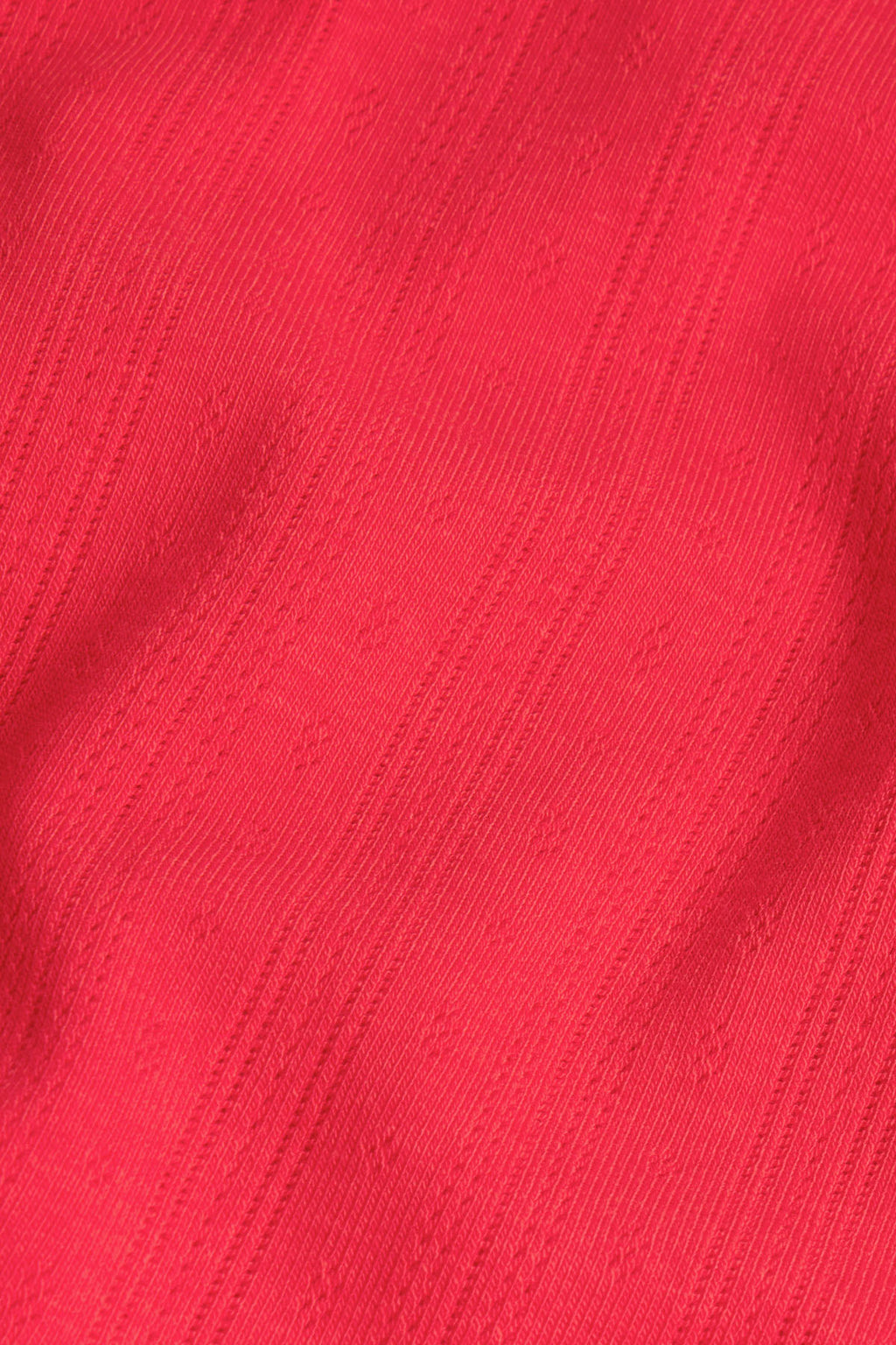 Red pointelle knit fabric with vertical ribbed texture and small perforated holes throughout.