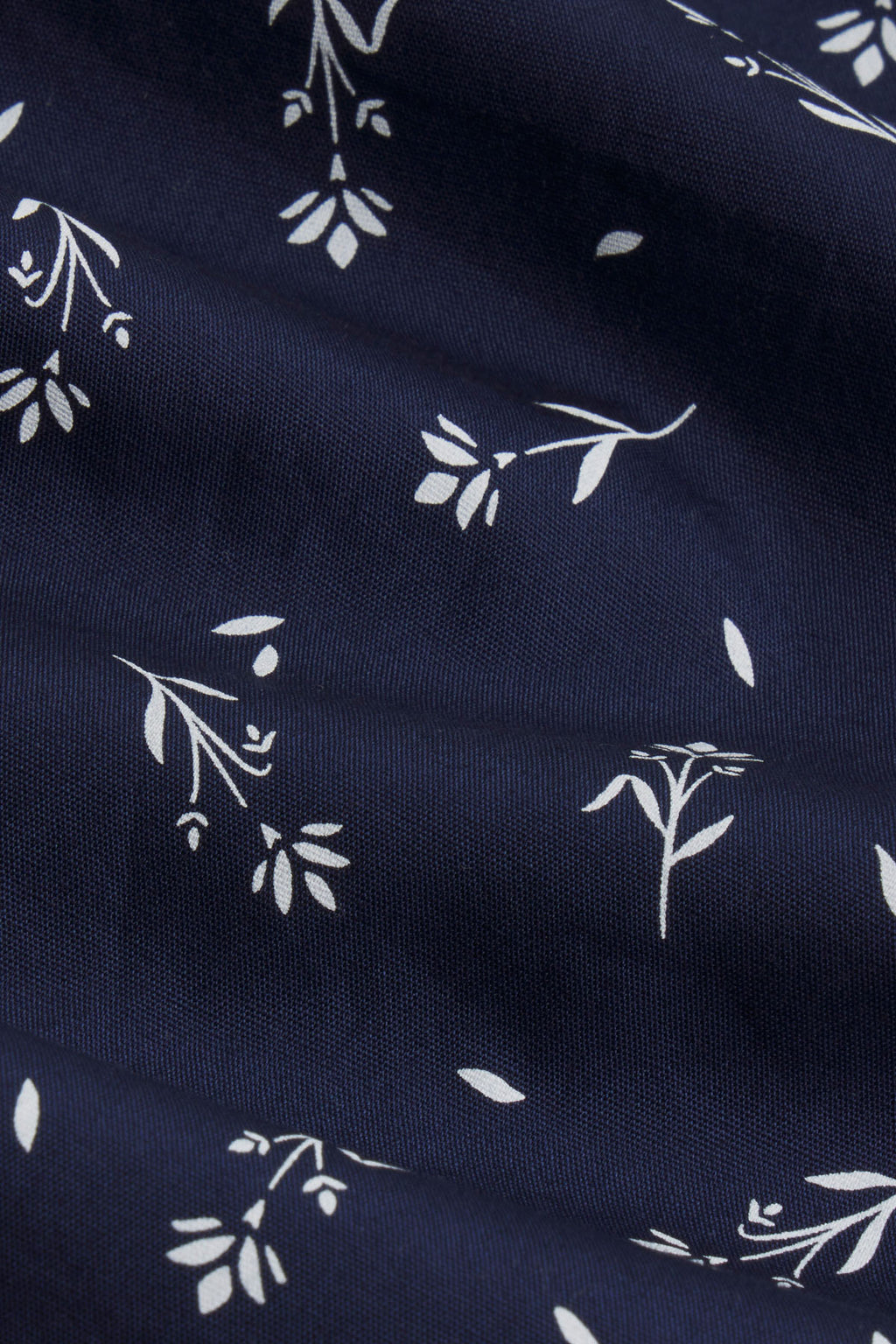 Navy poplin fabric with white botanical leaf print pattern.