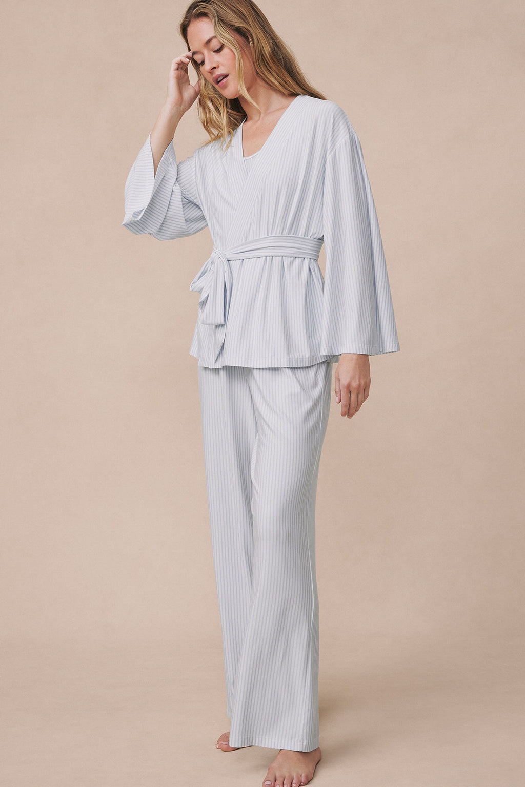 Woman wearing light gray ribbed kimono robe with tie belt over matching wide-leg pants in three-piece set.