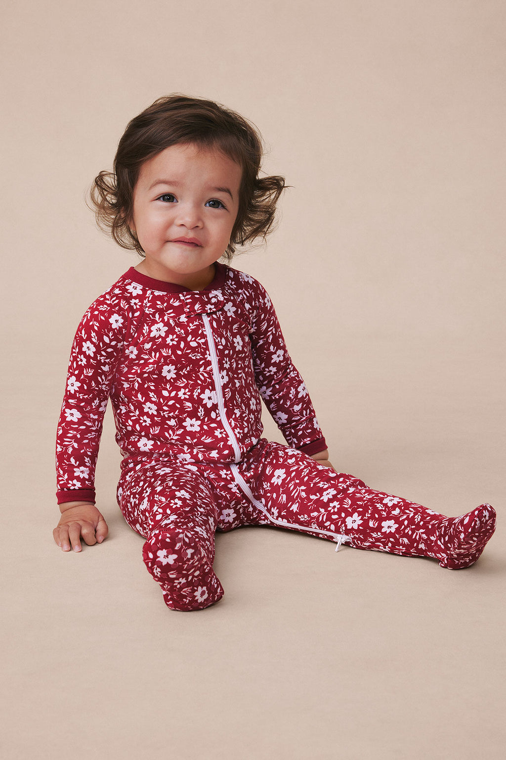Toddler wearing burgundy long-sleeve sleeper with white floral print and front zipper.