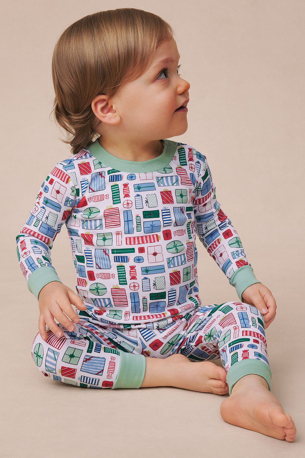 Toddler wearing long-sleeve top and pants with geometric print in red, blue, and green with sage green cuffs.