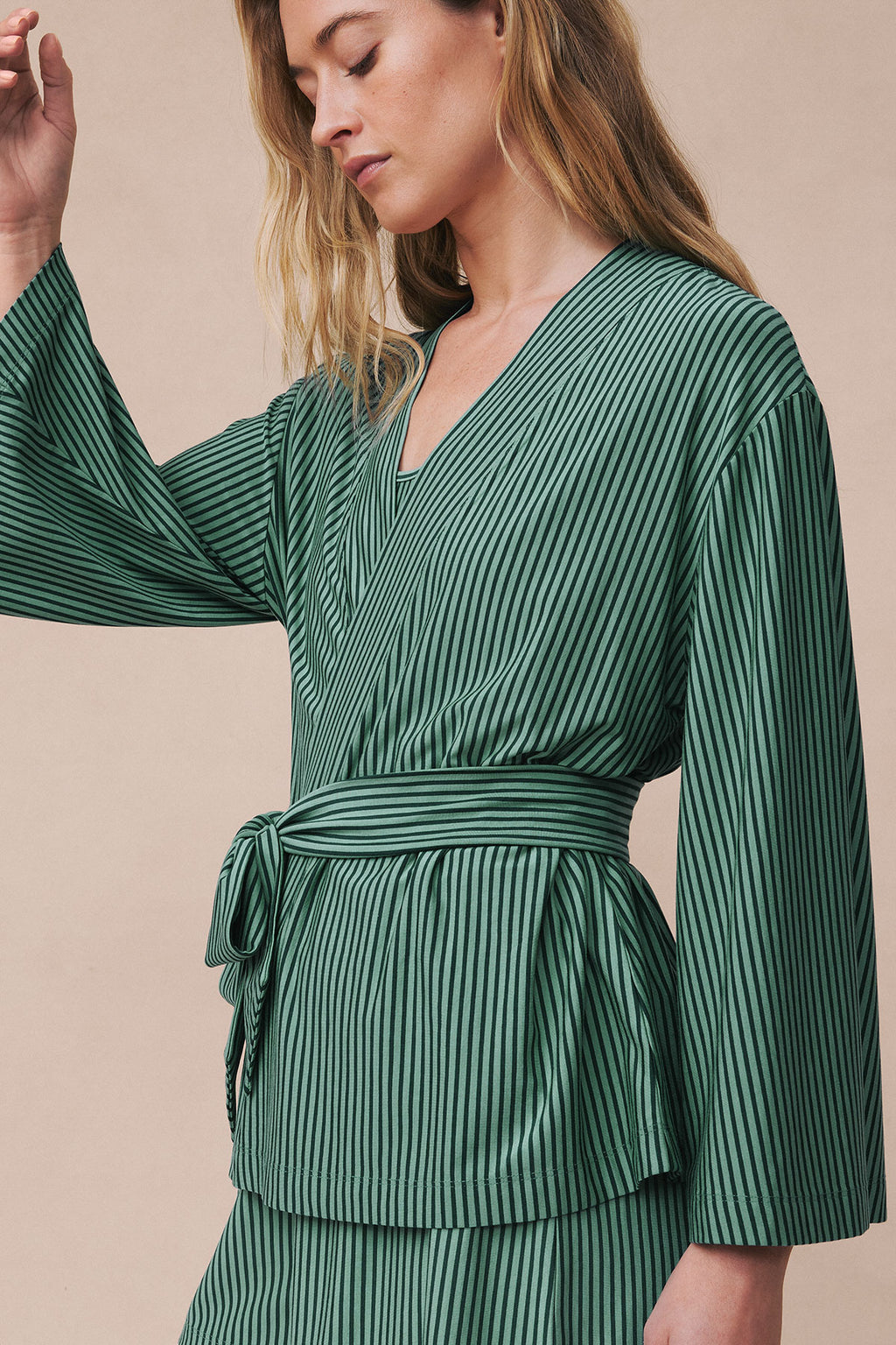 Woman wearing boxwood pencil-striped kimono with long sleeves and tie waist, paired with matching shorts.