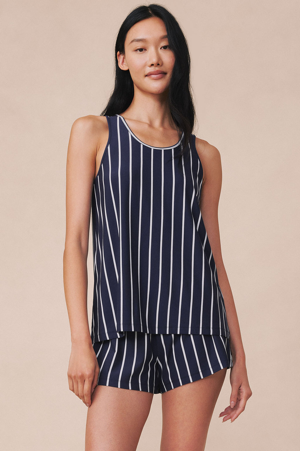 Woman wearing navy tank top and shorts with white vertical stripes.