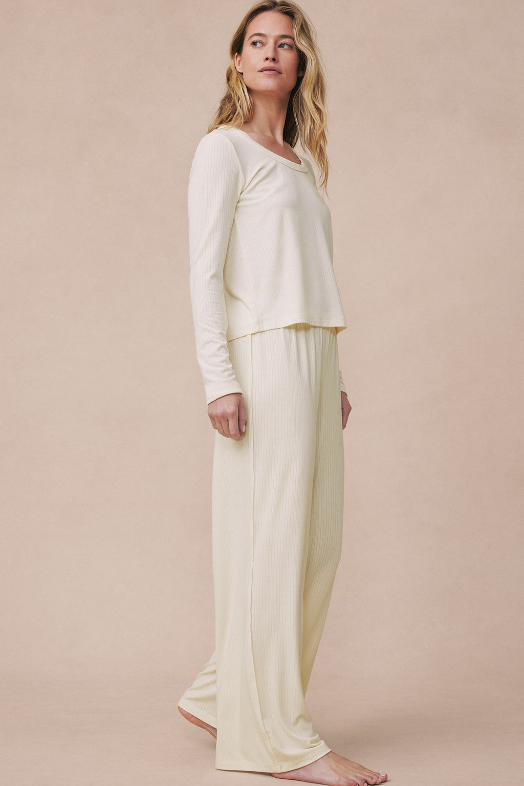 Ivory two-piece pajama set with long-sleeve scoop neck top and matching ribbed pants worn by model.