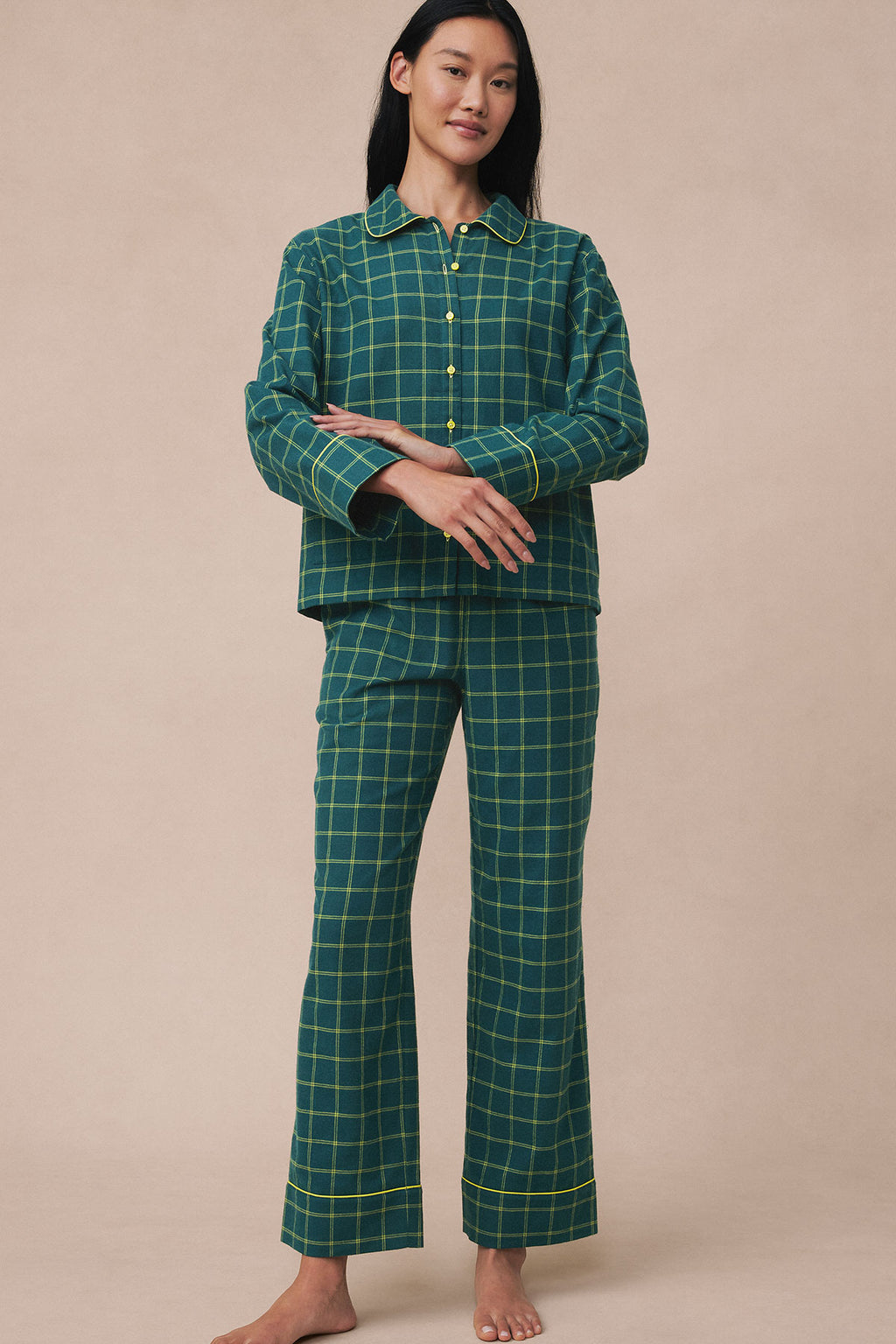 Woman wearing dark teal and yellow windowpane flannel pajama set with collared shirt and cropped pants.