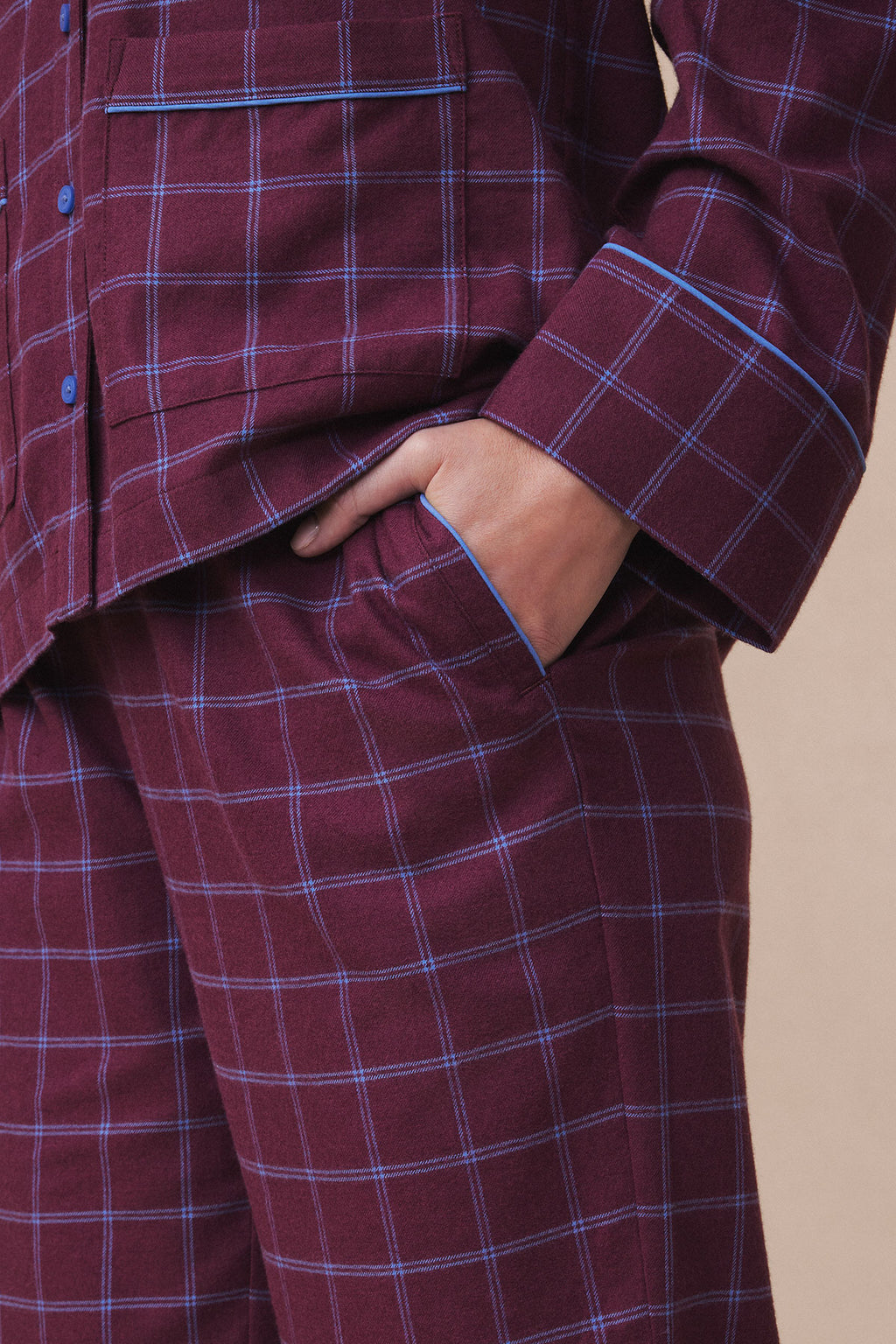 Burgundy flannel pajama set with blue windowpane plaid pattern, blue trim, and button front shirt worn with matching pants.