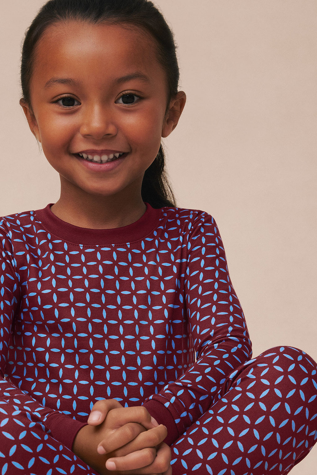 Child wearing burgundy long-sleeve top and pants with blue starburst pattern throughout.