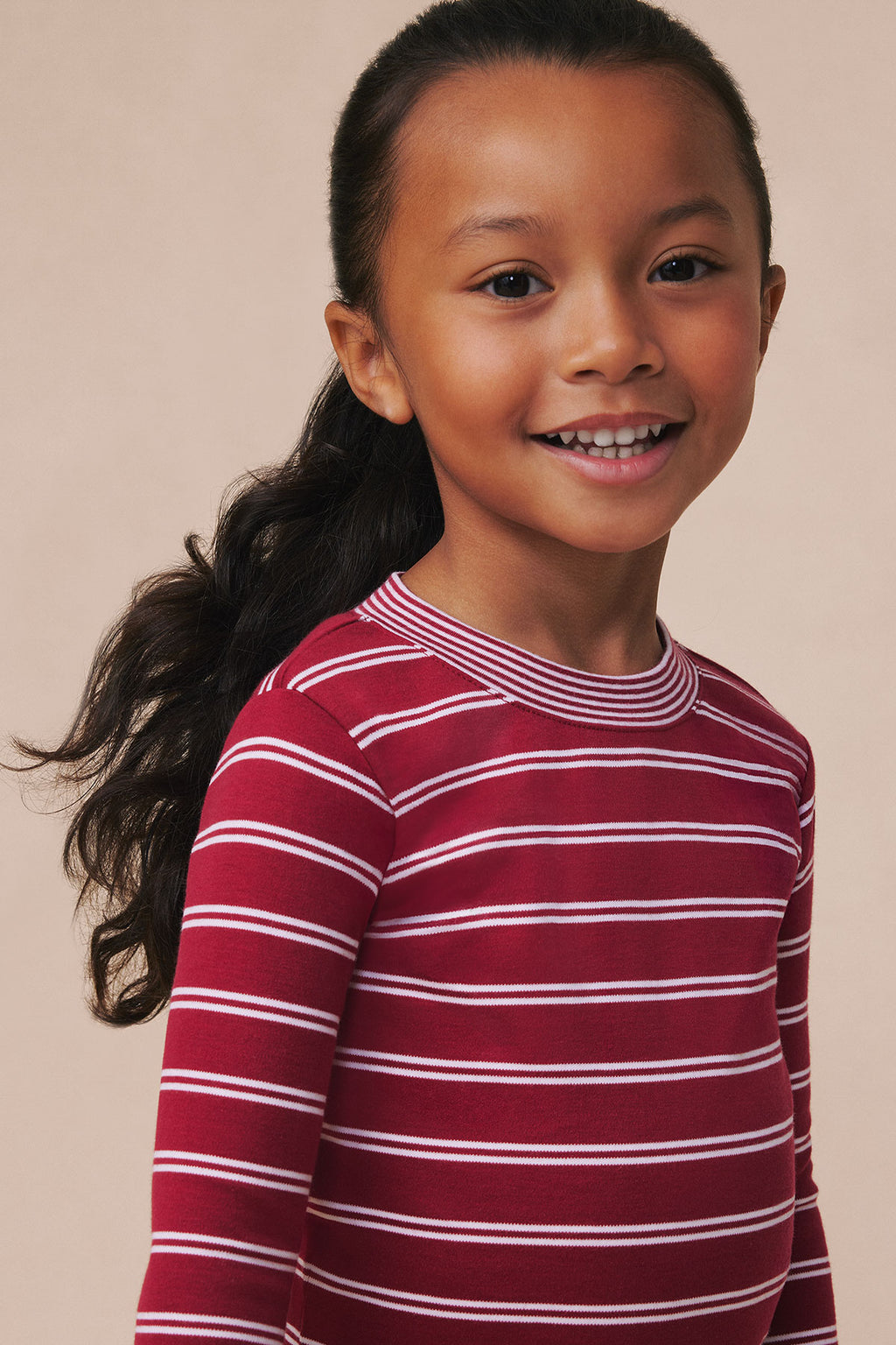 Child wearing garnet and white horizontal striped long-sleeve shirt.