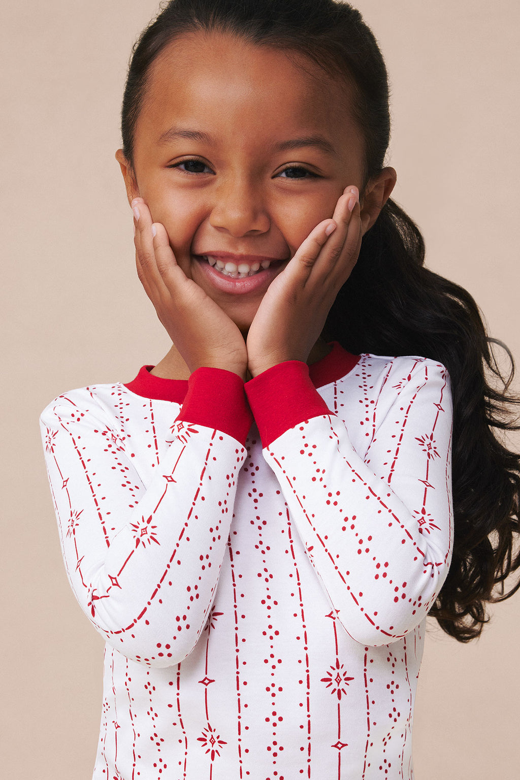 Child wearing long-sleeve top with white base and red geometric stripe pattern, featuring red collar detail.